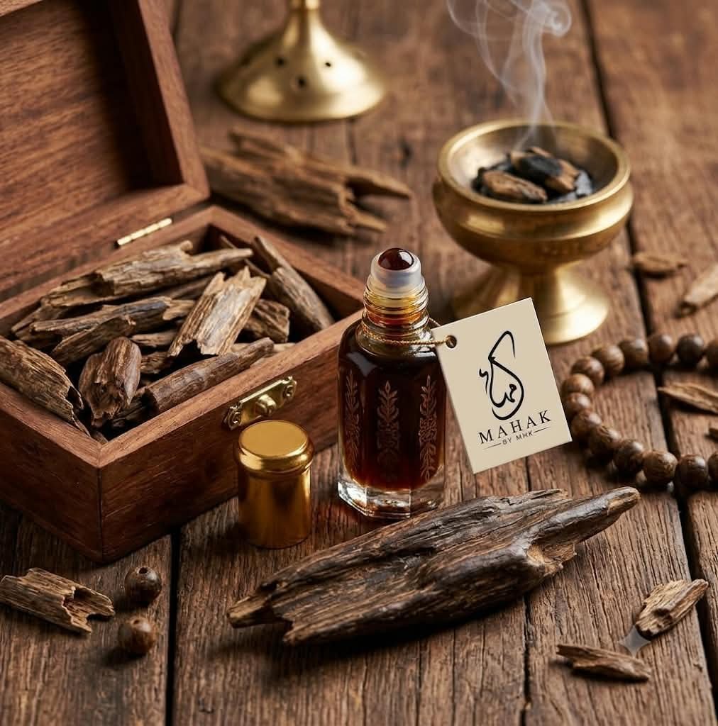 A MAHAK oudh attar roll-on bottle beside a wooden box of oudh wood chips and a brass incense burner
